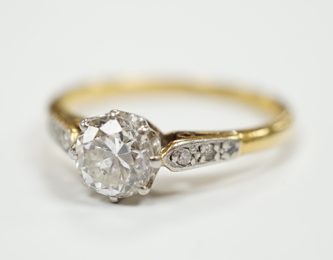 An 18ct, plat. and single stone diamond ring, with diamond set shoulders, the central stone measuring 6mm in diameter.